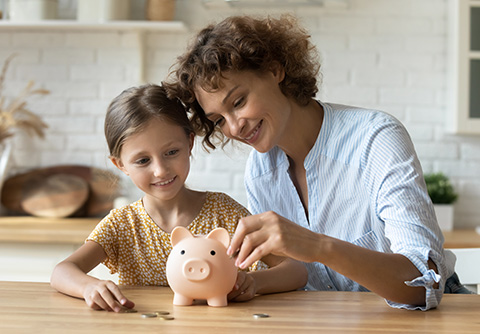 A mother and daughter with a piggy bank saving money
